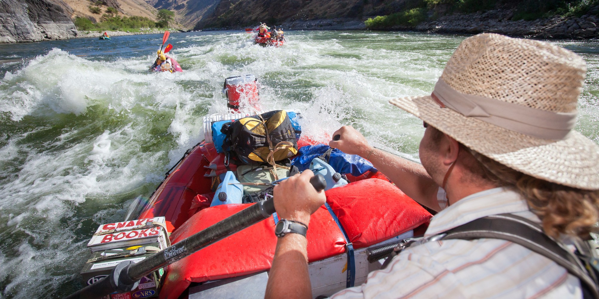 Downstream angle of an oarsmen in a red raft rowing through a rapid on the Snake River