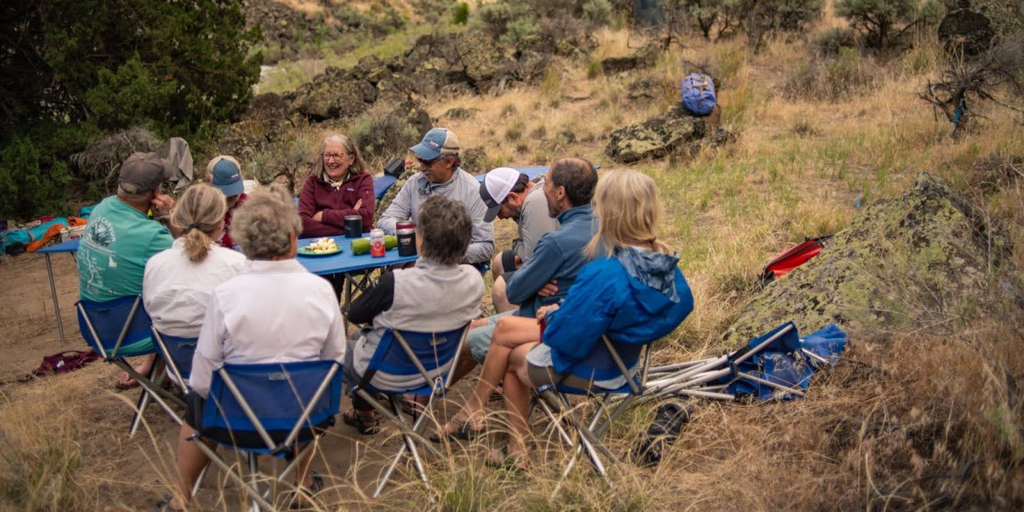 People camping gathered around a table laughing together