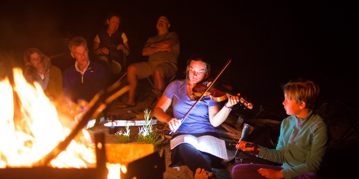 girl playing the violin while camping
