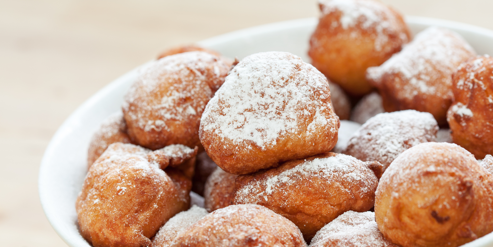 Close up of a bowl of beignets topped with powdered sugar