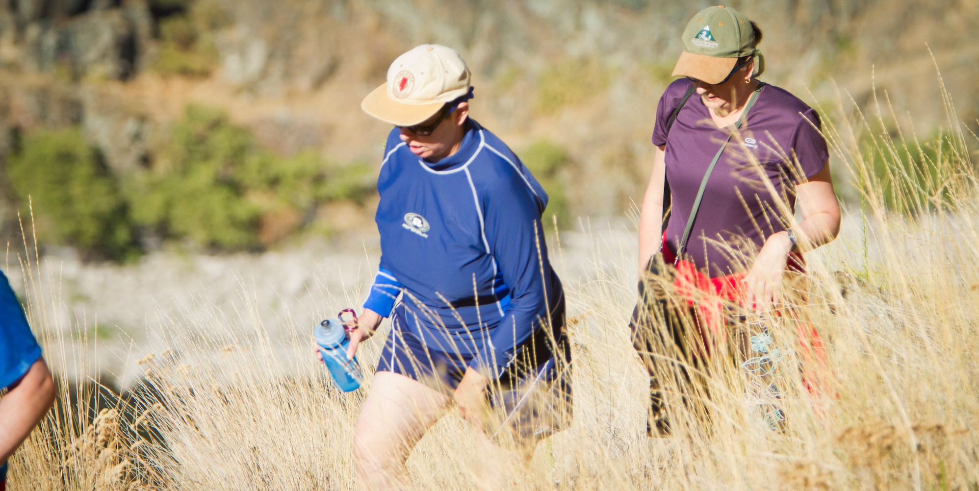 Guests hiking through tall desert grass with their waterbottles on a hot and sunny summer day 