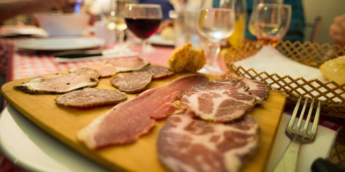Traditional Corsican cured meats displayed on a cutting board next to a glass of red wine