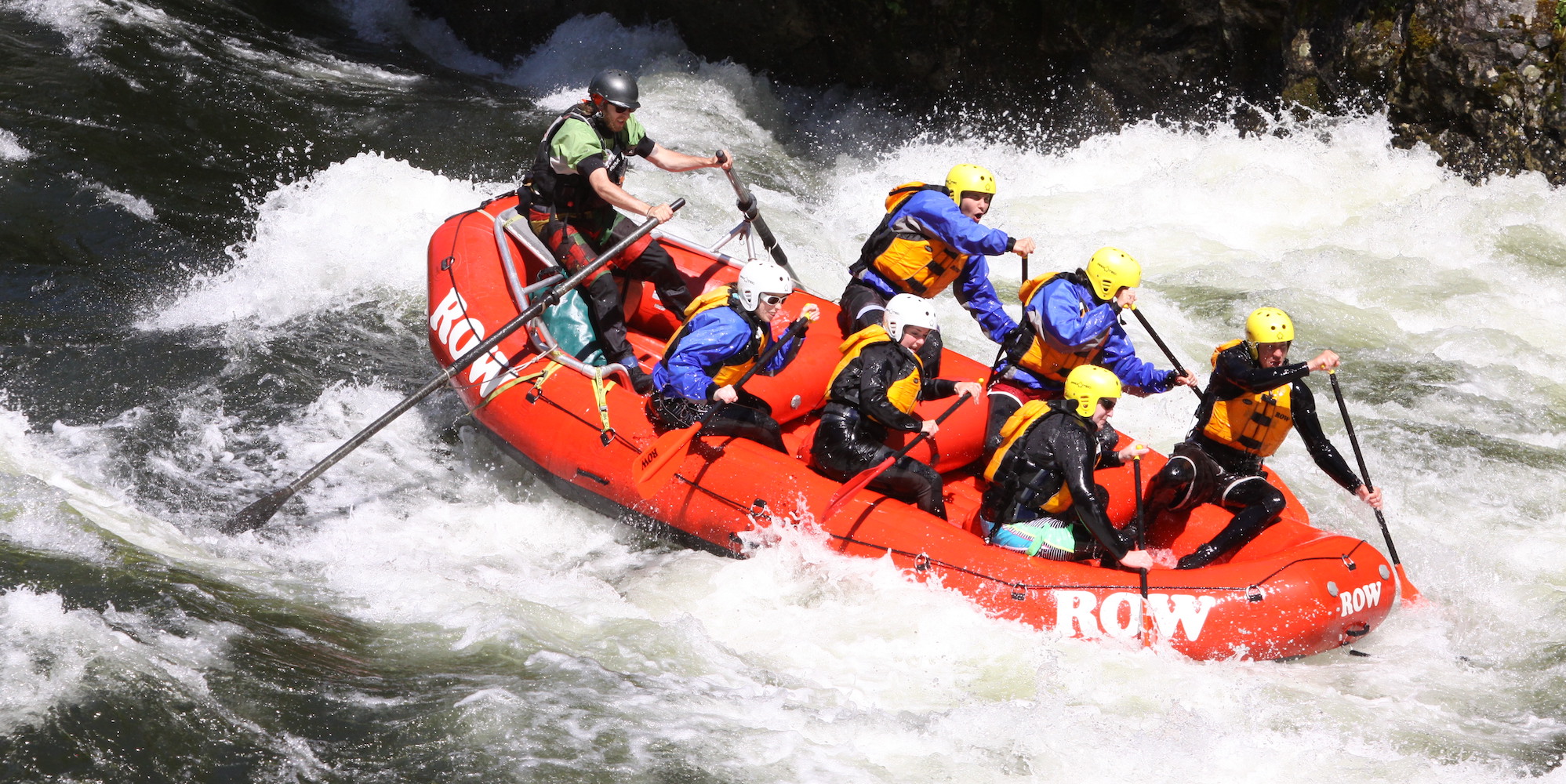 Six paddlers and a river guide on the oars rowing through a big whitewater rapid on Idahos best big water river