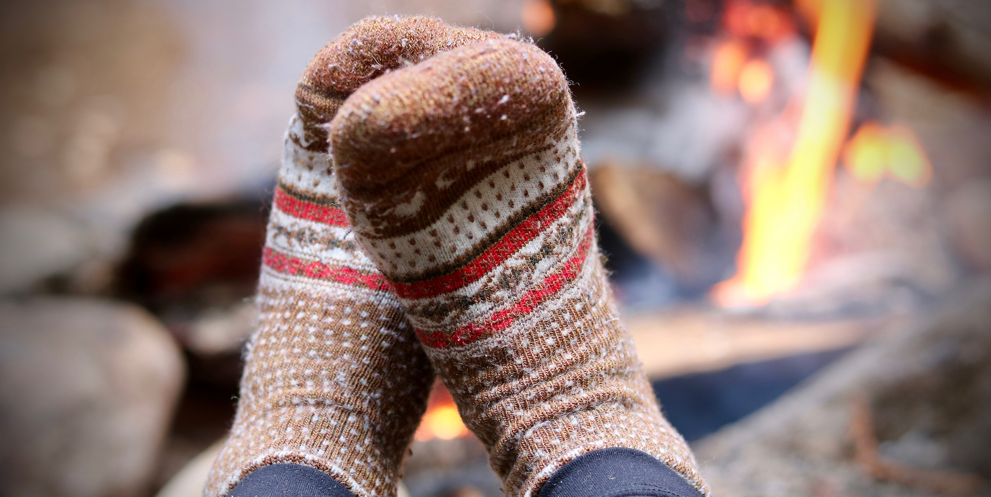 Pilled merino wool brown socks up against a campfire 