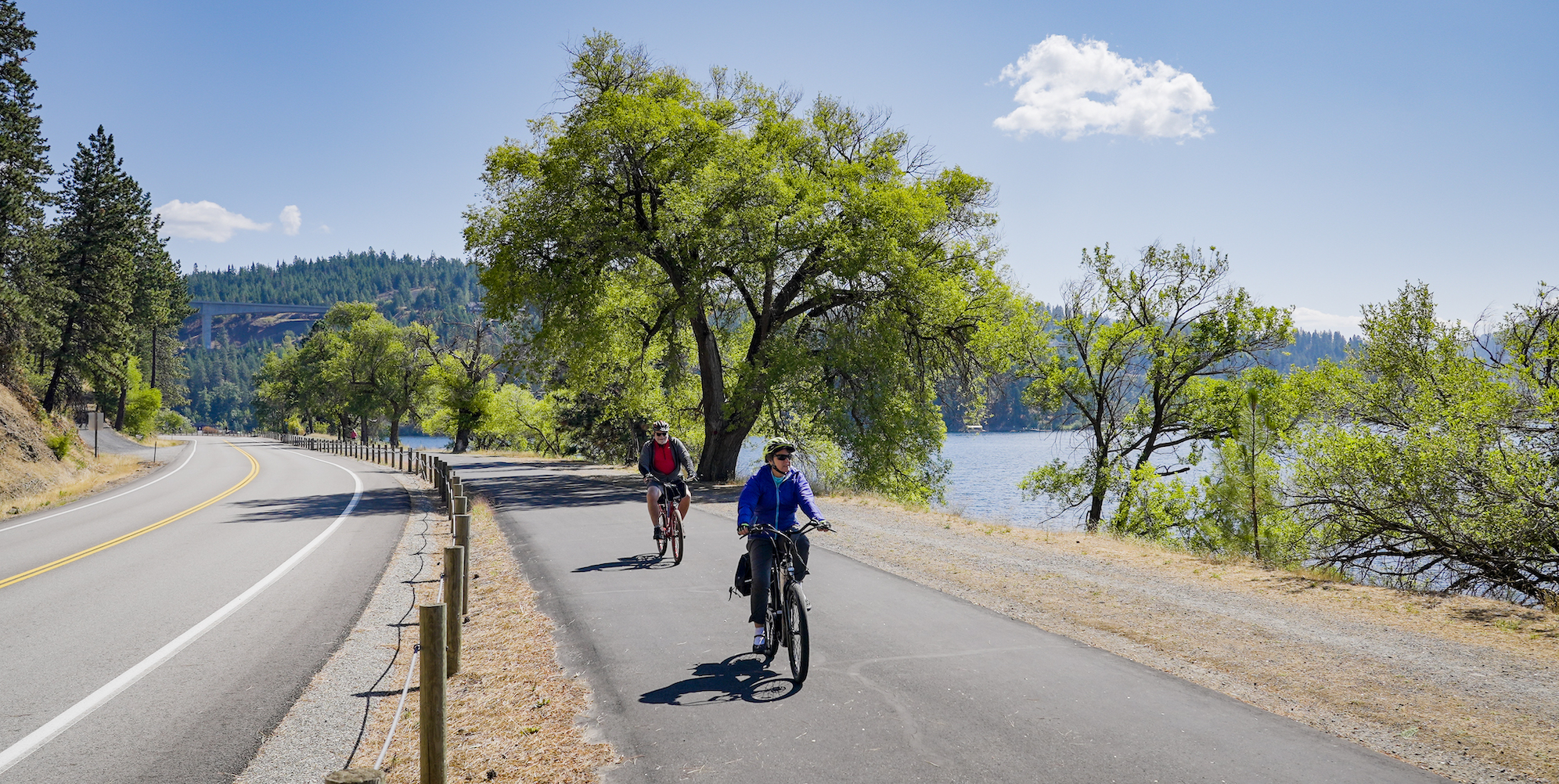 Two people riding their bikes on a paved trail in Coeur d'Alene, Idaho