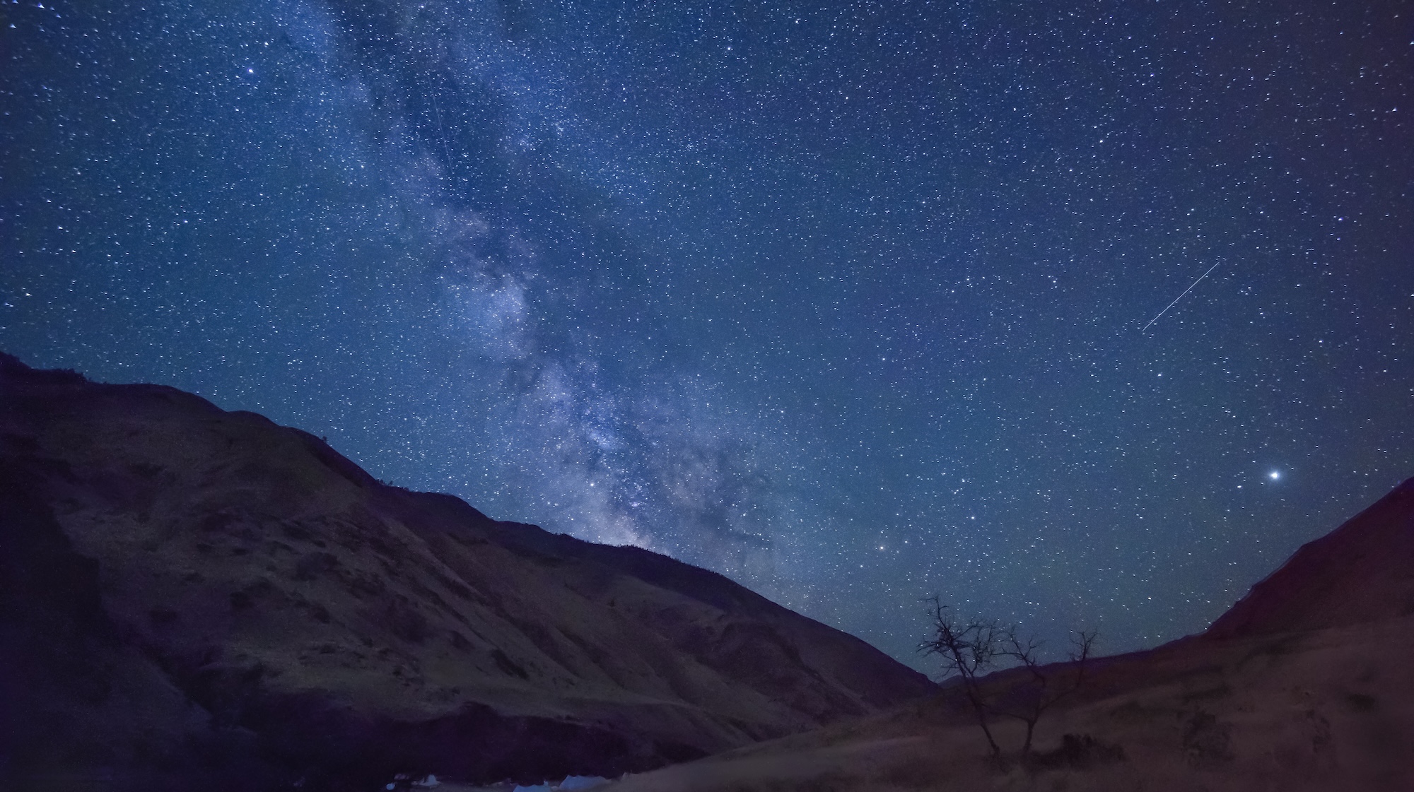 Bright Milky Way rising over a dark river canyon during a wilderness stargazing trip.