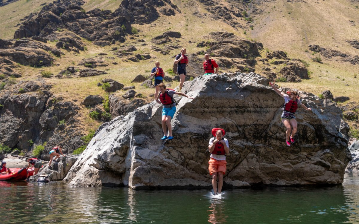 A Row Adventures river rafting group jumping off rocks