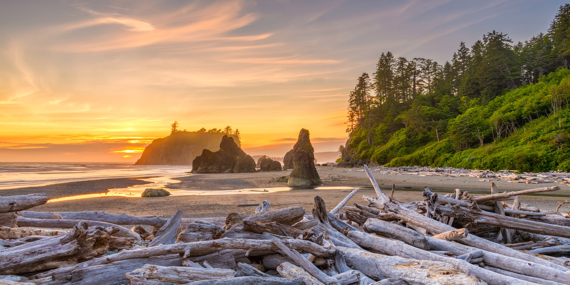 Sunset at Ruby Beach in Olympic National Park with driftwood, sea stacks, and glowing skies over the Pacific Ocean.