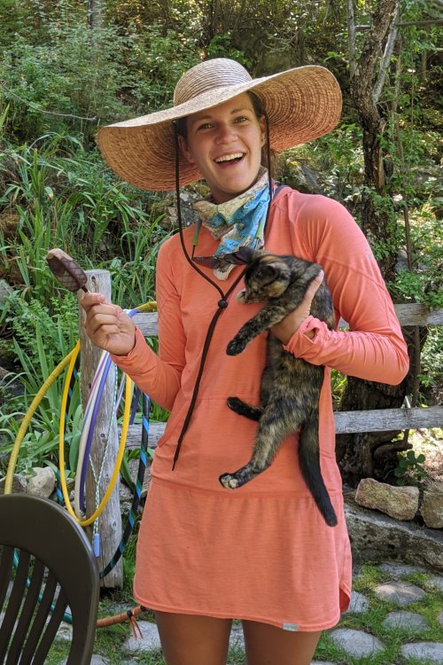 female with pink dress and sun hat holding a cat