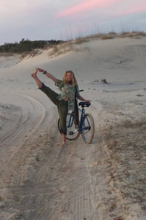 girl posing with a bike on a sandy trail