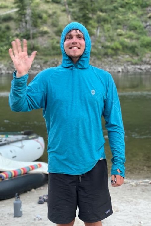 river guide in blue hoodie along a river