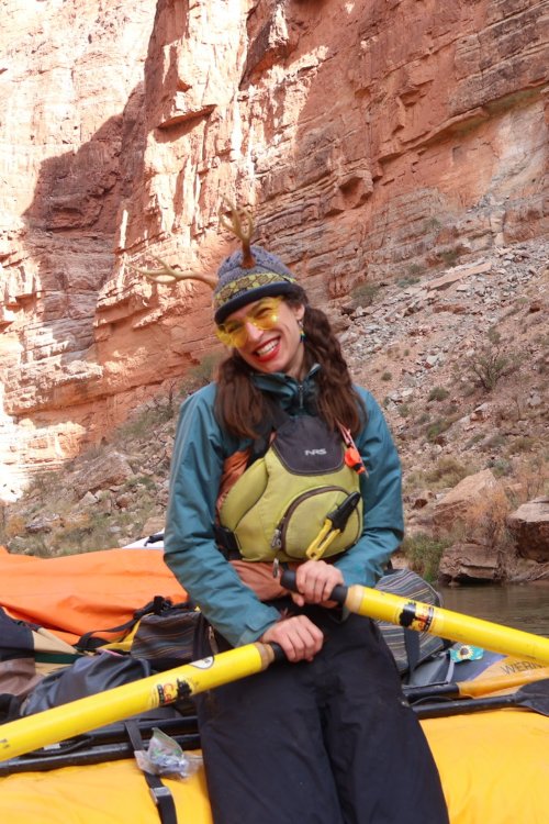 ROW Adventures guide Jade sitting on a yellow boat with oars in her hands.