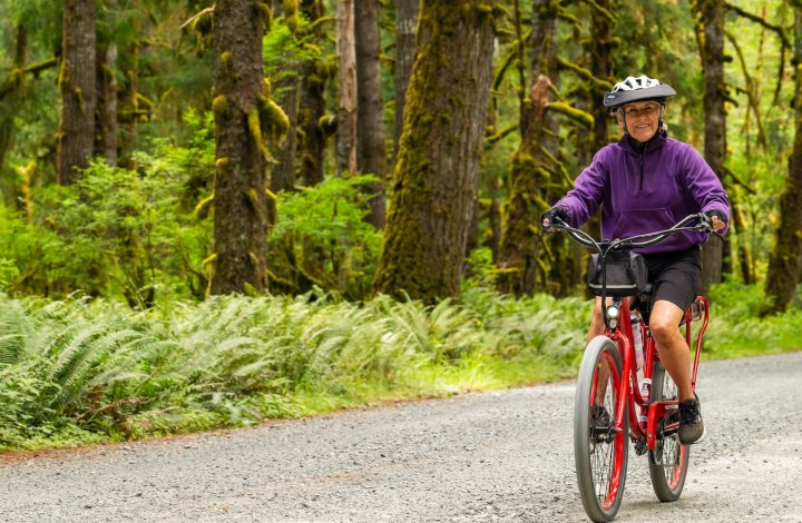 A woman biking through Olympic National park on an e-bike and hike tour with ROW adventures.