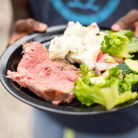 Steak, mashed potatoes, and salad on a black plate while camping in Salmon Idaho