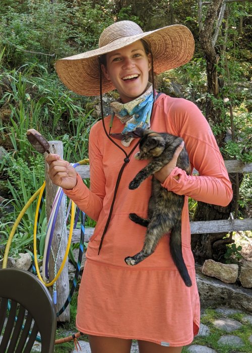 female with pink dress and sun hat holding a cat