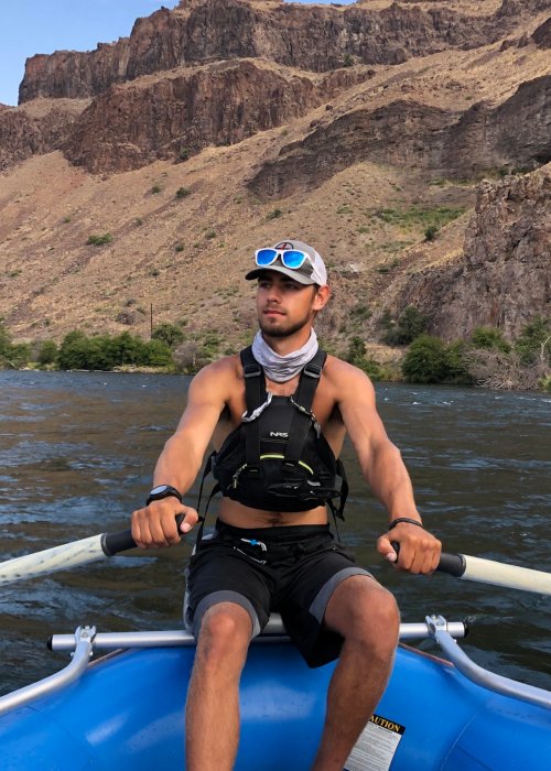 man in blue raft holding oars