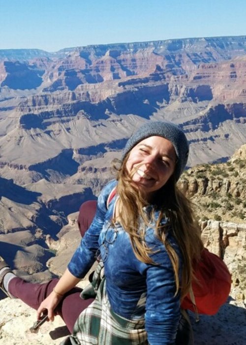 female sitting on top of deep desert canyon