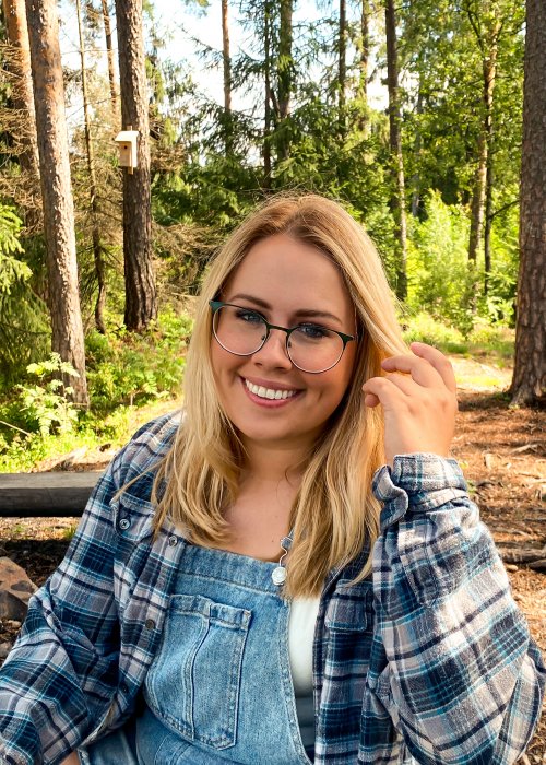 female with overalls and flannel on in wooded area