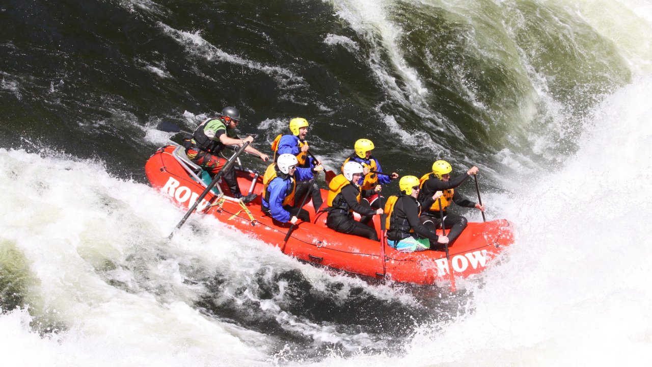 Six paddlers with yellow helmets in a red raft paddling through a big whitewater rapid on the Lochsa River in Idaho