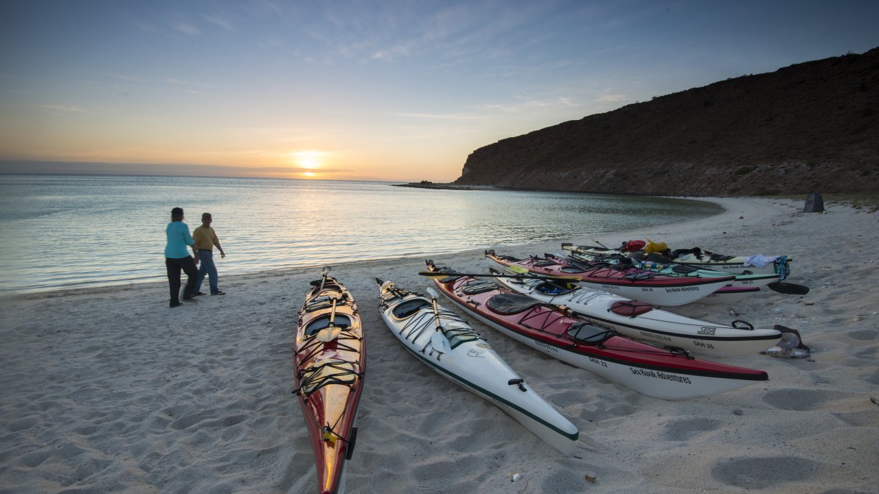 Guests take a stroll on the beach where their kayaks are docked in Isla Espiritu Santo, Baja