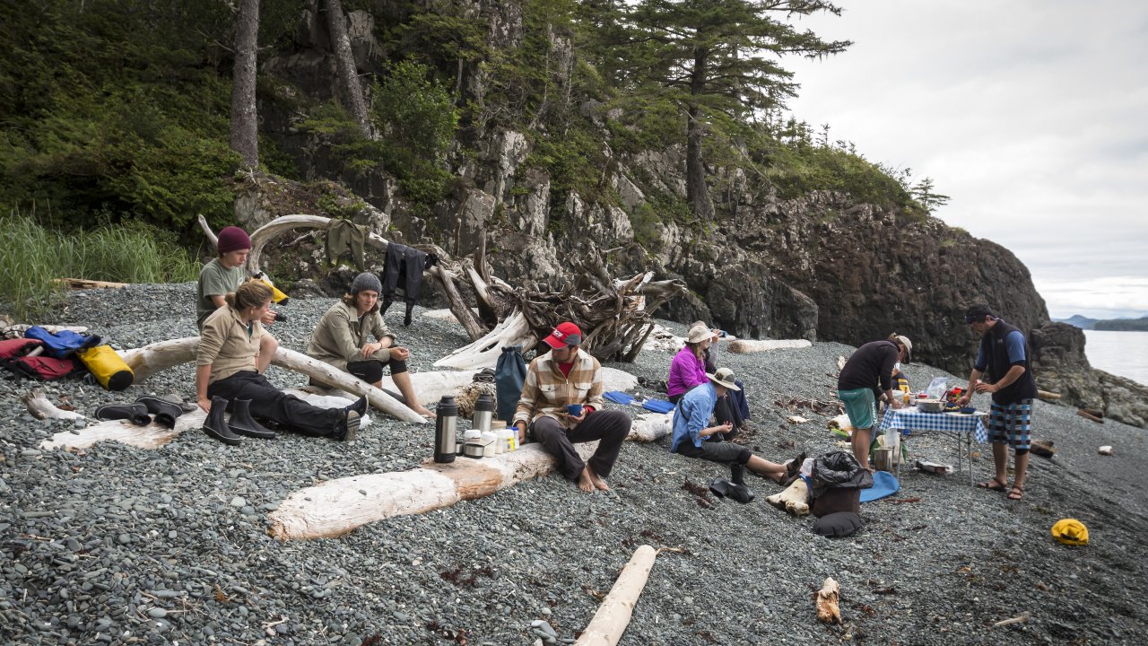 Guests sprawl gear on the beach at their stop for lunch while sea kayaking