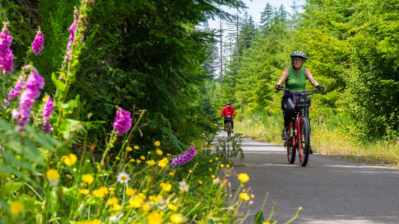 Women biking on a paved trail through wildflowers in Washington
