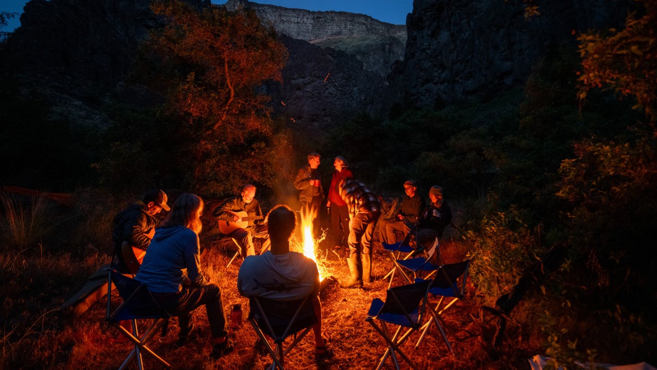 People sitting around a campfire while camping along the Bruneau River