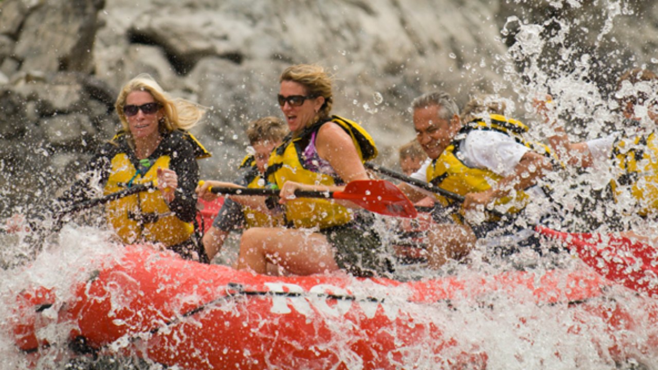 people in whitewater raft getting splashed by water
