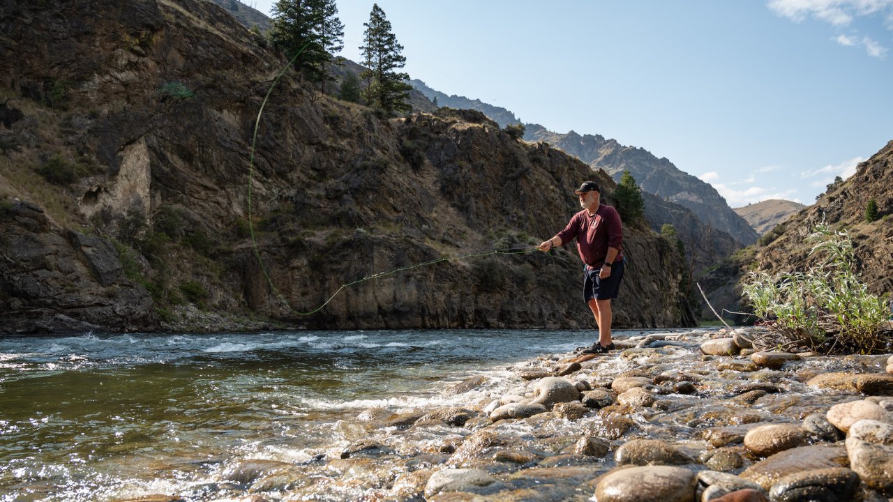 Person casting a fly fishing line into the Middle Fork Salmon River from a rocky river bed