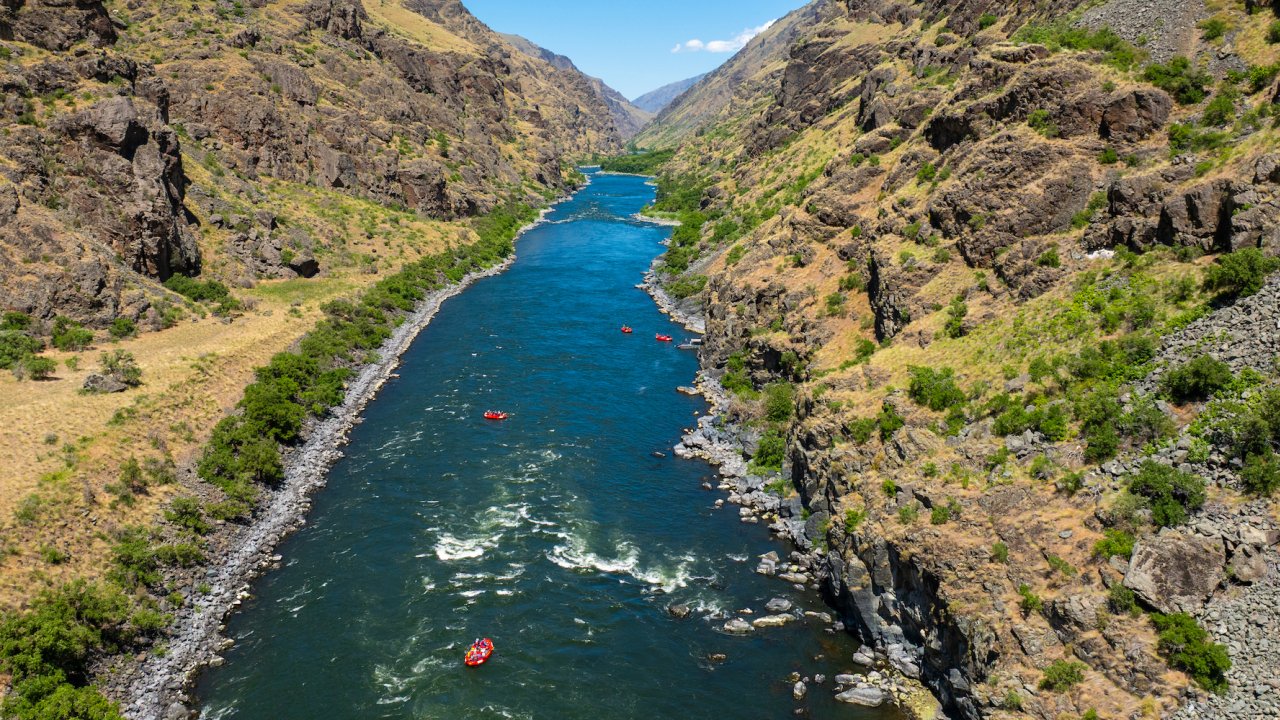 Birds eye view of red ROW rafts floating down stream on the Snake River