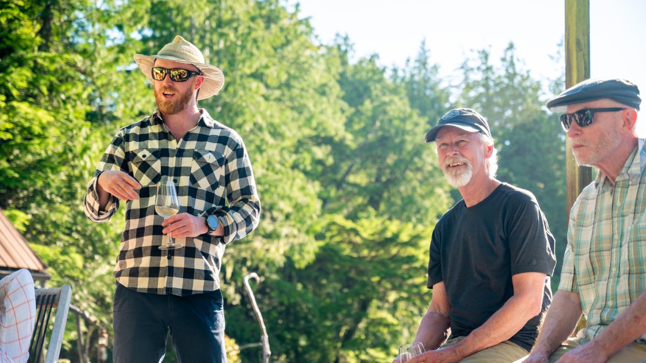 Three travelers smiling and laughing together on a sunny afternoon in British Columbia