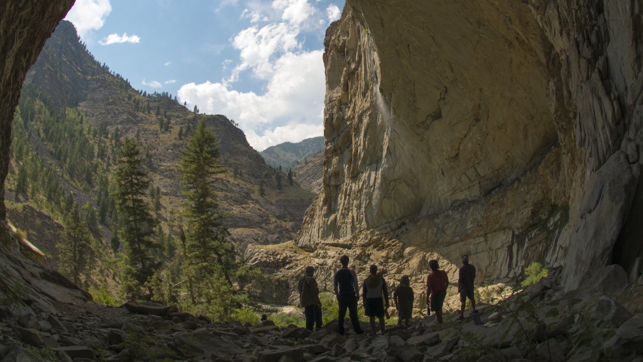 A group of people from the back looking up at a rock structure on a hike along the Salmon River in Idaho