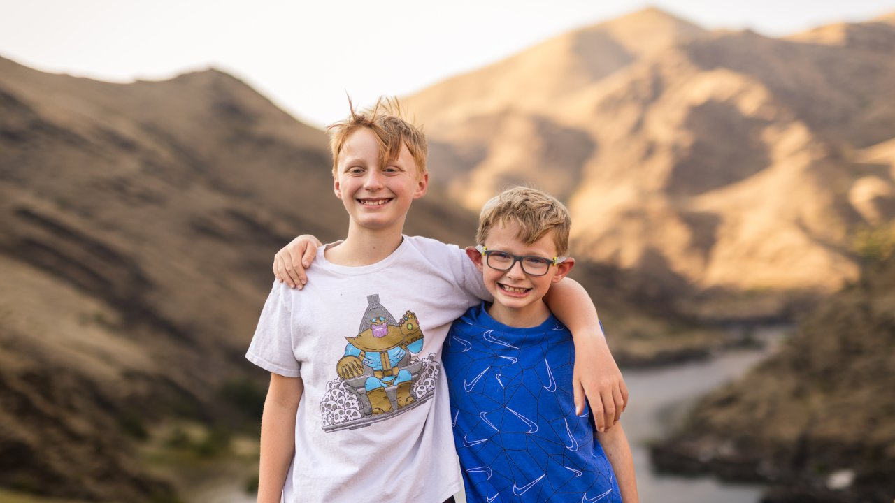 Two brothers under the age of 10 smiling while on a hike together in Idaho
