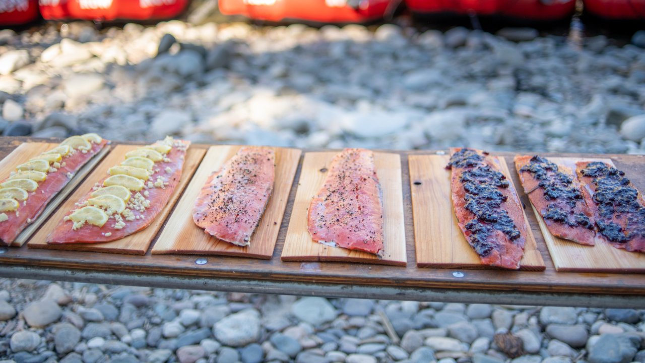 6 filets of salmon on cedar planks on a table ready to be cooked