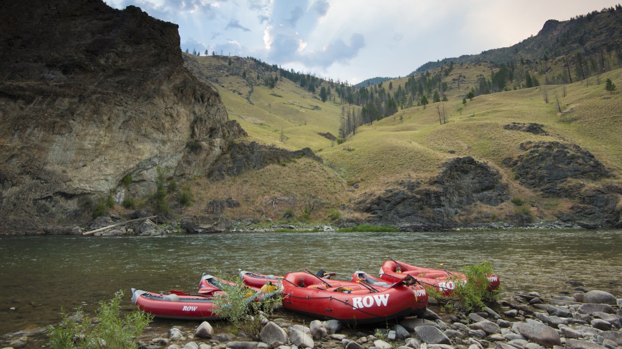 Red rafts tied up to shore along the Salmon River on a cloudy day
