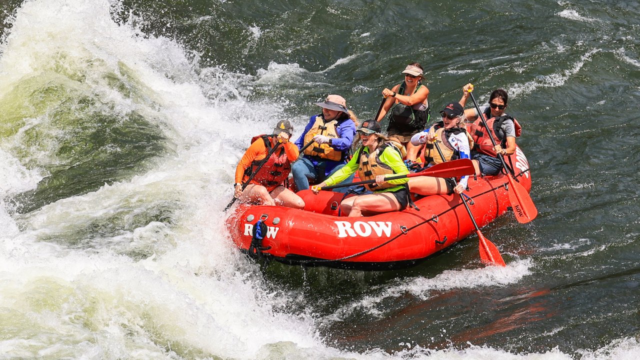 A red raft full of guests and one guide about the enter a wave in a rapid on the Clark Fork River