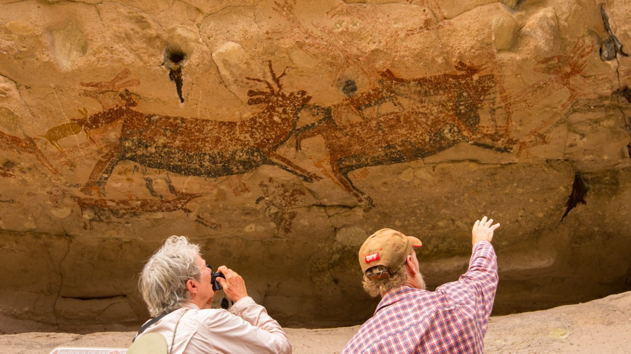 Two tourists pointing and taking pictures of the ancient cave paintings in Santa Teresa Canyon, Baja California