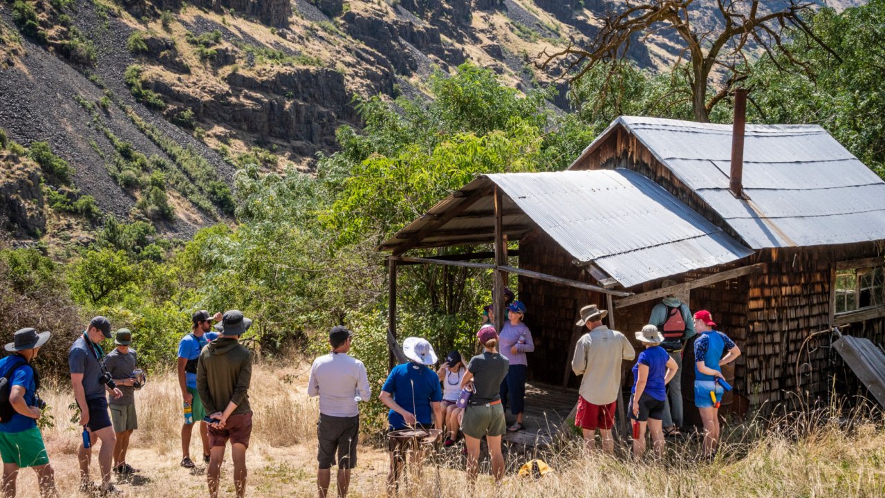 Group of people exploring a pioneer homestead while on a whitewater rafting trip on the Snake River through Hells Canyon