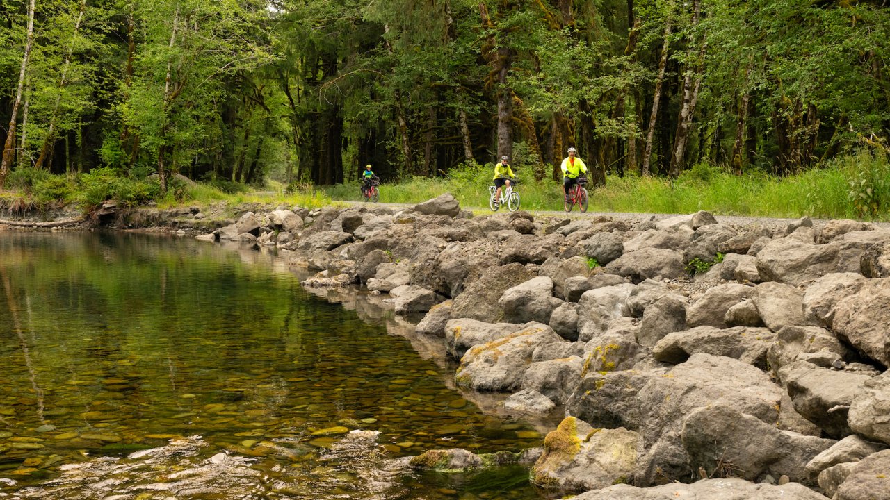 Group of people biking along a paved trail next to a river in Olympic National Park