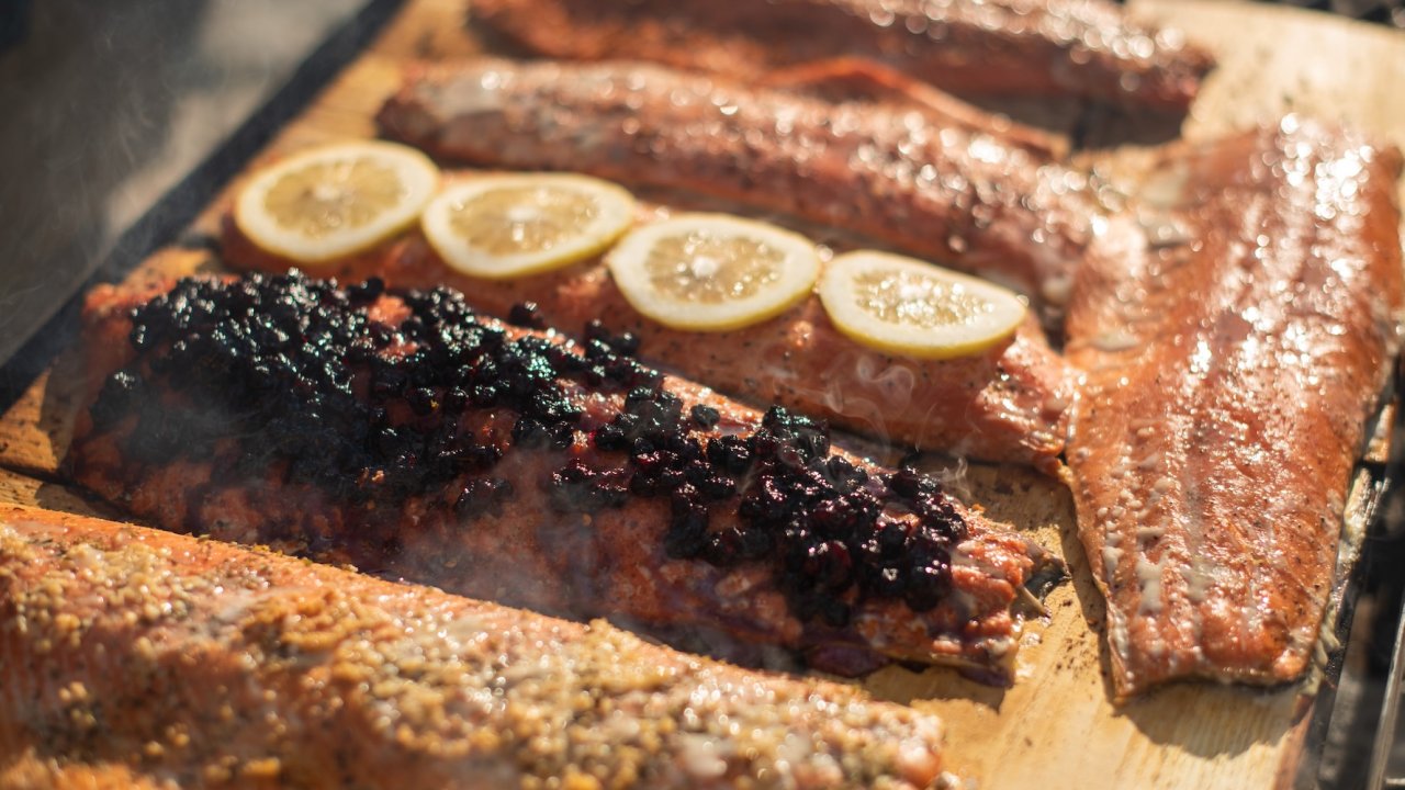 Freshly grilled Idaho salmon topped with herbs, berries, and lemon slices, a nourishing meal highlighting local cuisine on an Idaho wellness travel retreat.