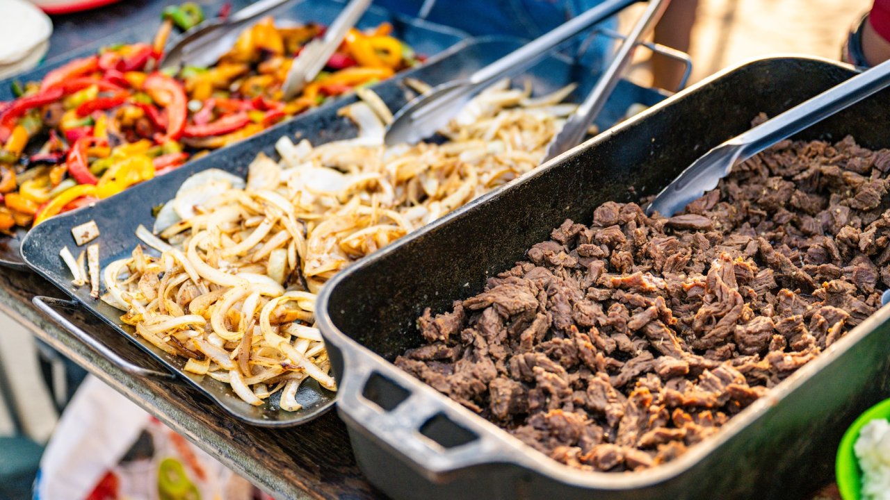 Freshly cooked meal with grilled vegetables, onions, and sliced meat prepared outdoors.