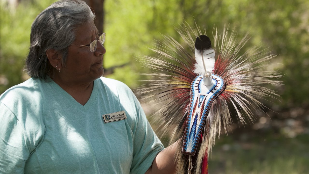 Indigenous cultural educator sharing traditional regalia during a Salmon River conservation trip, highlighting Native knowledge and heritage on public lands.