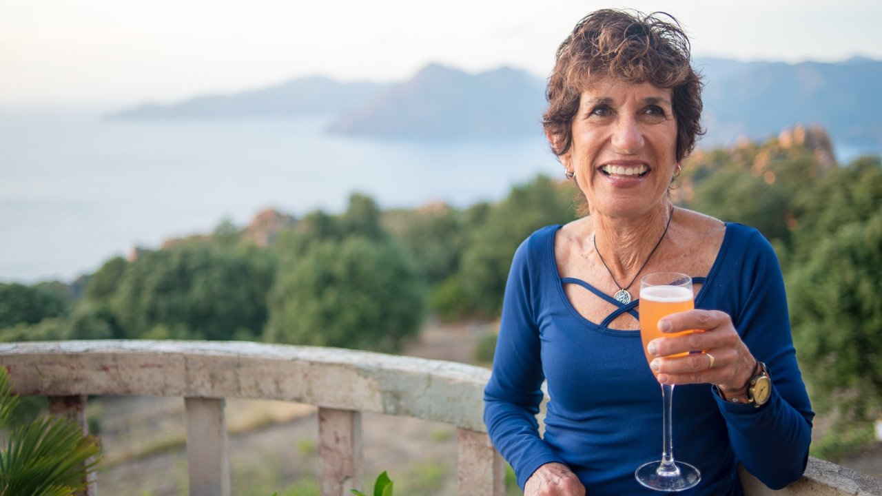 A guest enjoys an evening aperitif overlooking the Corsican coastline, a relaxed cultural moment on a small-group Corsica tour.