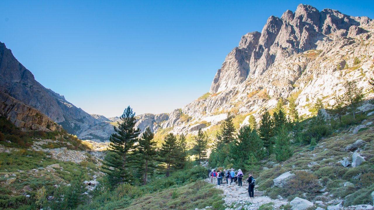 Hikers follow a mountain trail through Corsica’s dramatic interior, experiencing rugged landscapes on a guided Corsica hiking and sea kayaking tour.