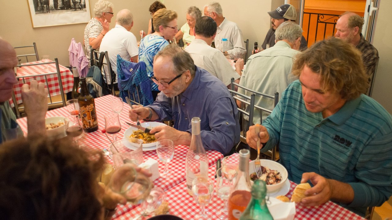 Travelers enjoy a shared dinner of traditional Corsican cuisine during a guided Corsica travel experience, highlighting local culture and community.