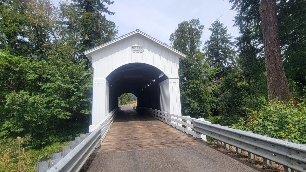 Cyclists riding through a historic white covered bridge along a scenic bike route in Oregon’s Willamette Valley.