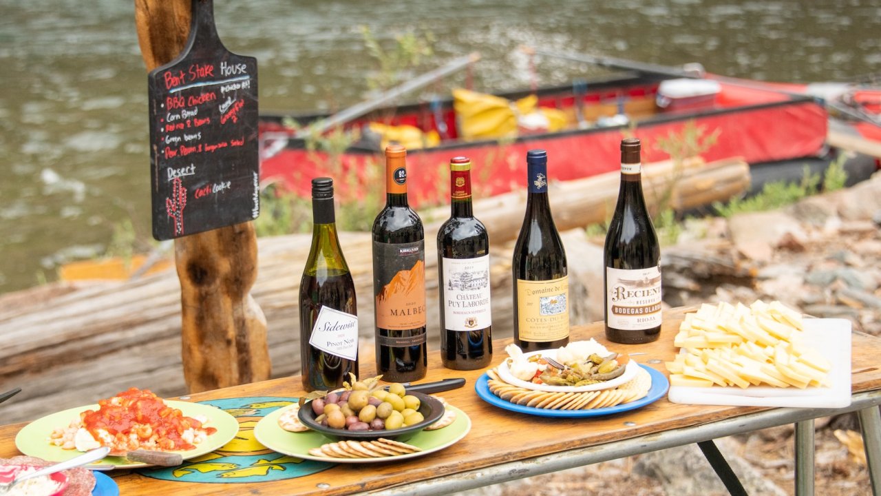 Wine, cheese, and appetizers arranged riverside during a gourmet meal on a Middle Fork Salmon River rafting tour.