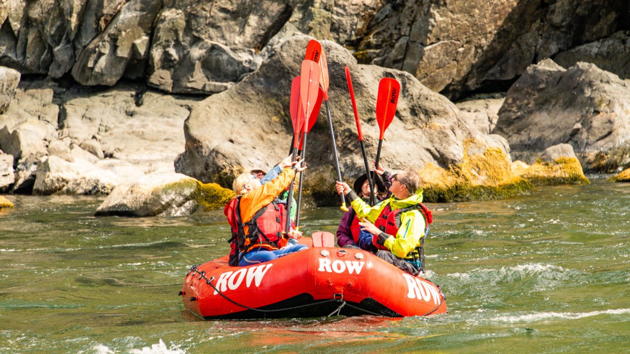 people giving a paddle high five in a red raft