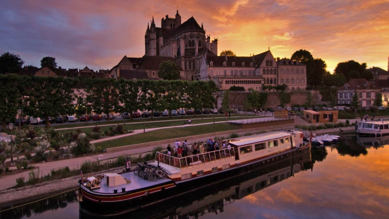 barge sitting in front of french city at sunset