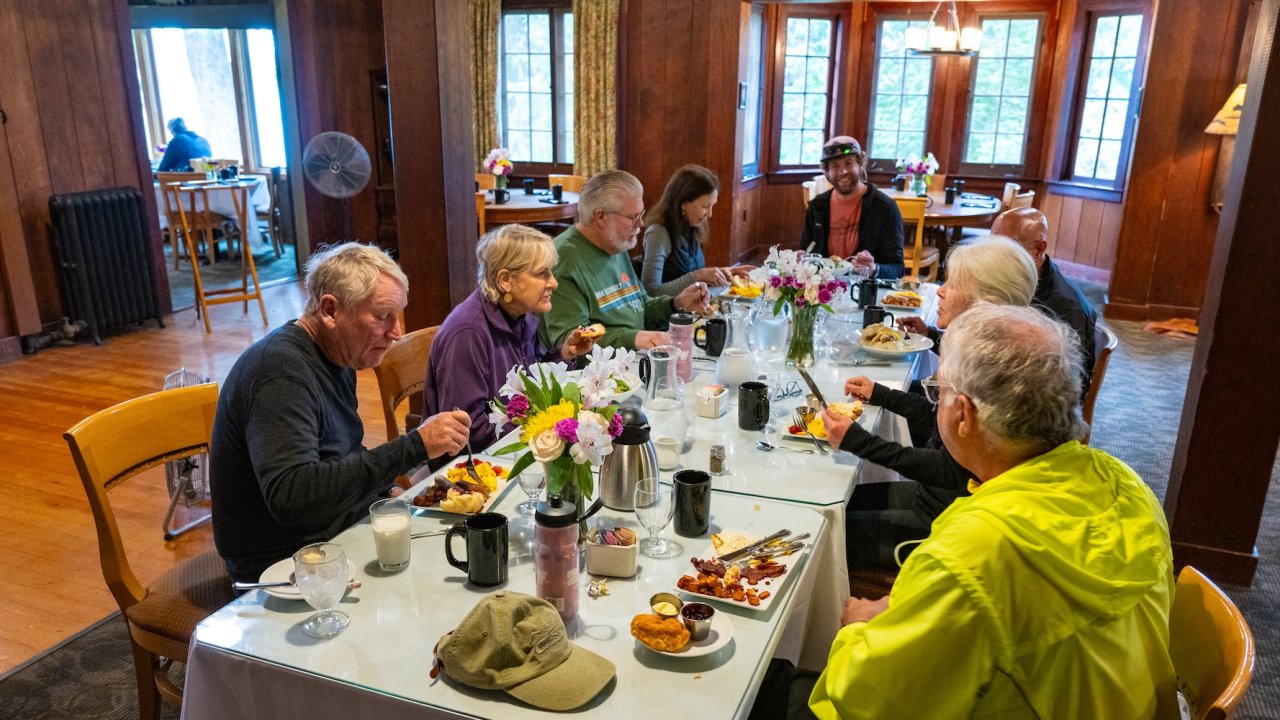 Cyclists enjoy a group meal inside a rustic lodge dining hall on an Olympic Peninsula biking tour in Washington.
